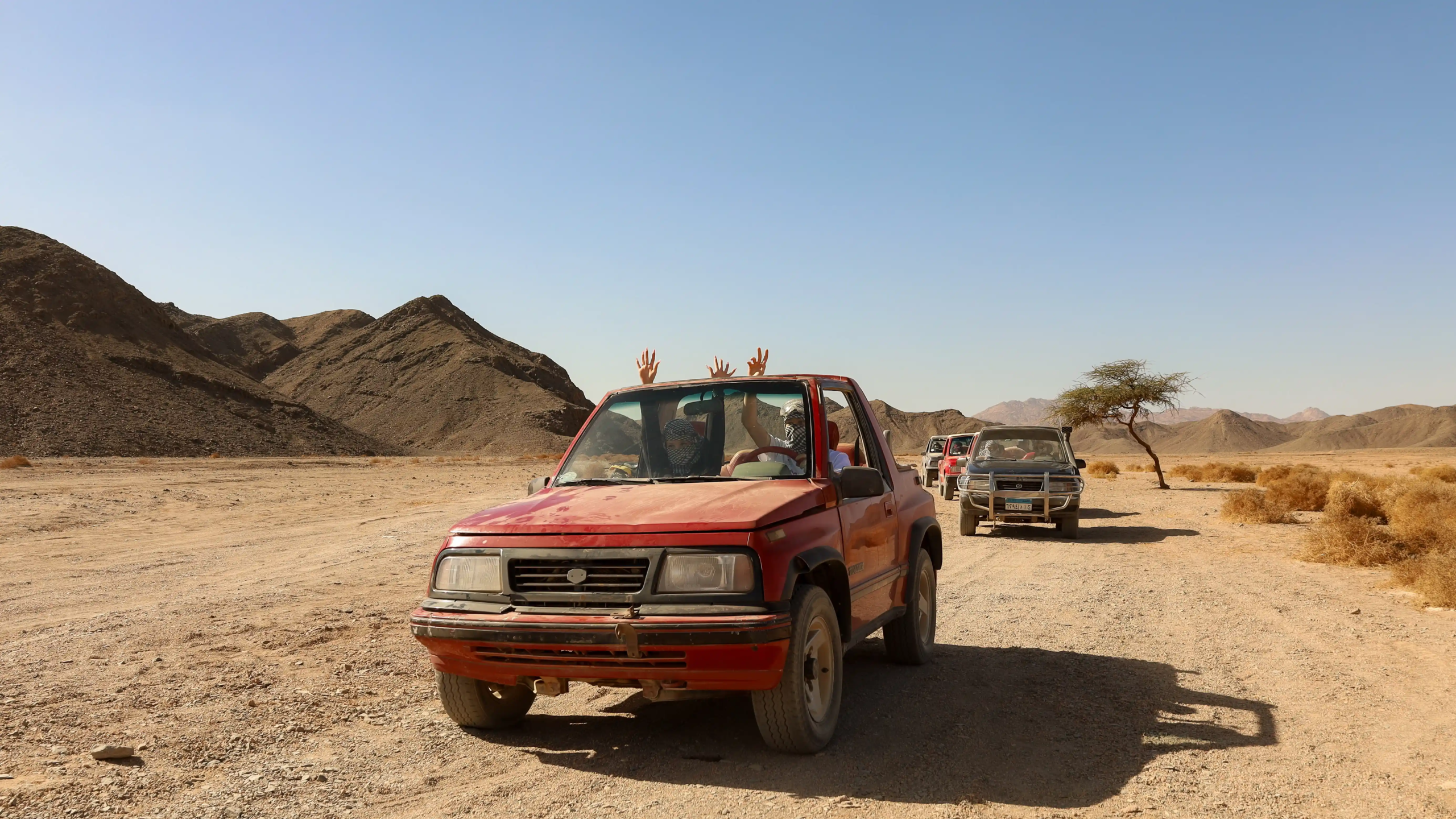 a tourist waving in sinbad safari a driving a red jeep in marsa alam desert photo by falcon photography